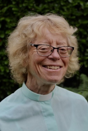 Sandra Faccini smiling outdoors, wearing a clerical collar